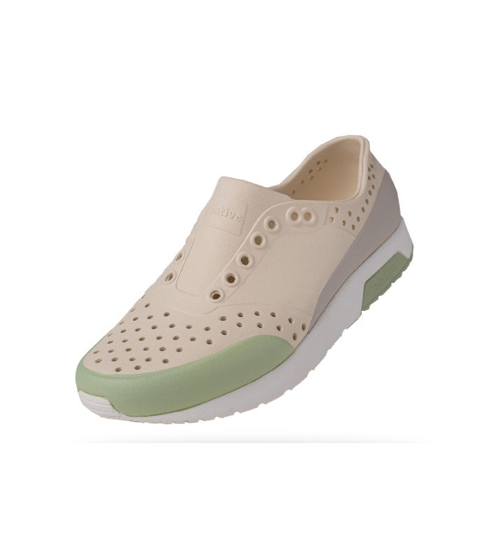 A women's EVA sneaker with a beige upper and green accents, featuring a perforated design and a flat sole.