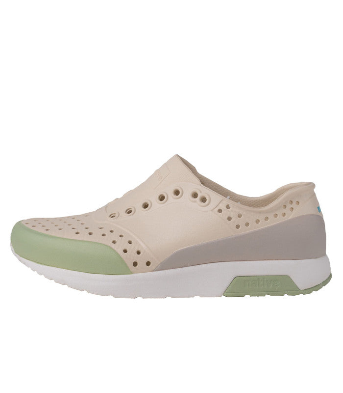 A women's EVA sneaker with a beige upper and green accents, featuring a perforated design and a flat sole.